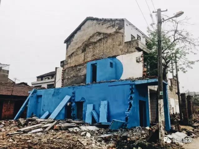 △ 這棟建筑是臨江最近的半拆遷建筑物的遺留，沅江和堤壩成為了展覽的天然背景。創作團隊對這棟建筑進行了半涂裝，將符號性的沅水曲線與拆遷進行中的建筑立面進行意義的疊造，它們共同觸發了場所空間多元語境的生成，把拆遷這種暫時破壞性、干擾性的介入行動與沅水右岸發展的未來性、美好性緊密融合。